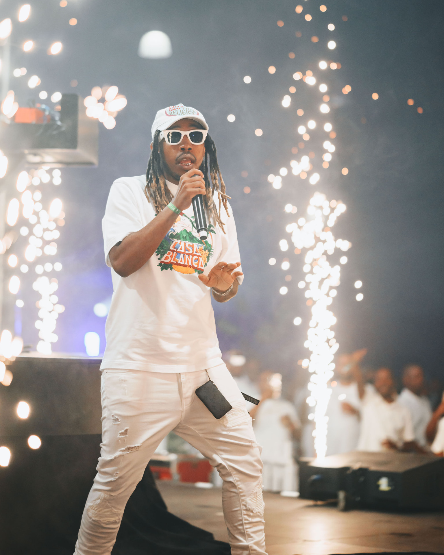 Performer on stage with pyrotechnics and bright lights at the main event
